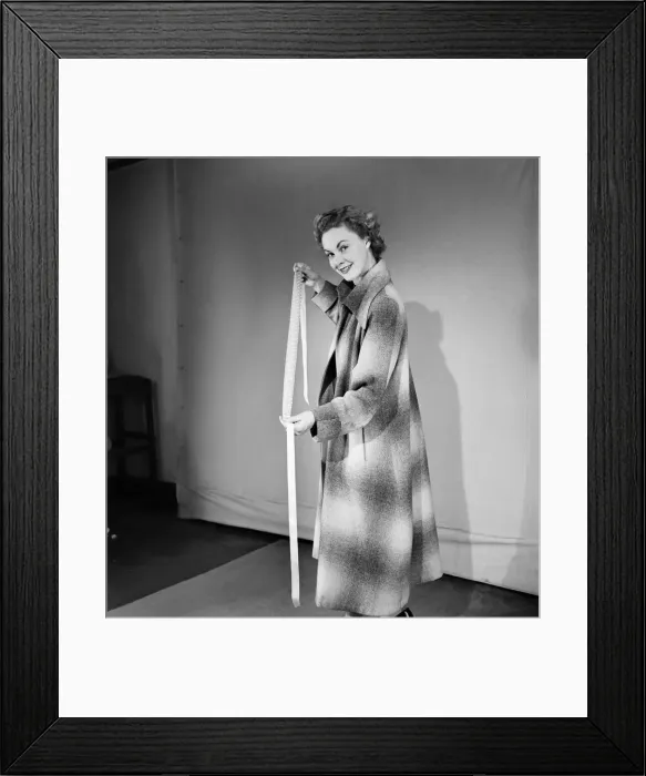 Framed Print : Woman poses wearing a long coat and holding a head scarf Framed Print : Woman poses wearing a long coat and holding a head scarf