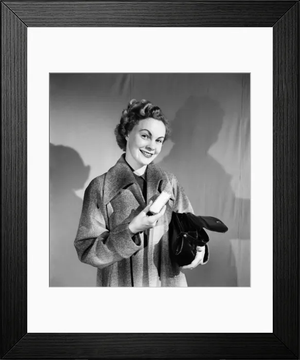 Framed Print : Woman poses wearing a long coat and holding a handbag. October 1952 C6273 Framed Print : Woman poses wearing a long coat and holding a handbag. October 1952 C6273