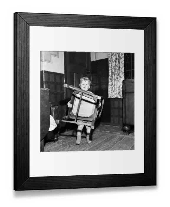 Framed Print : Young toddler boyholding a wooden chair December 1952 C6391-001