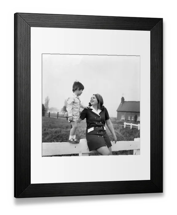 Framed Print : A woman outside with her son standing on a gate in a country field November 1969