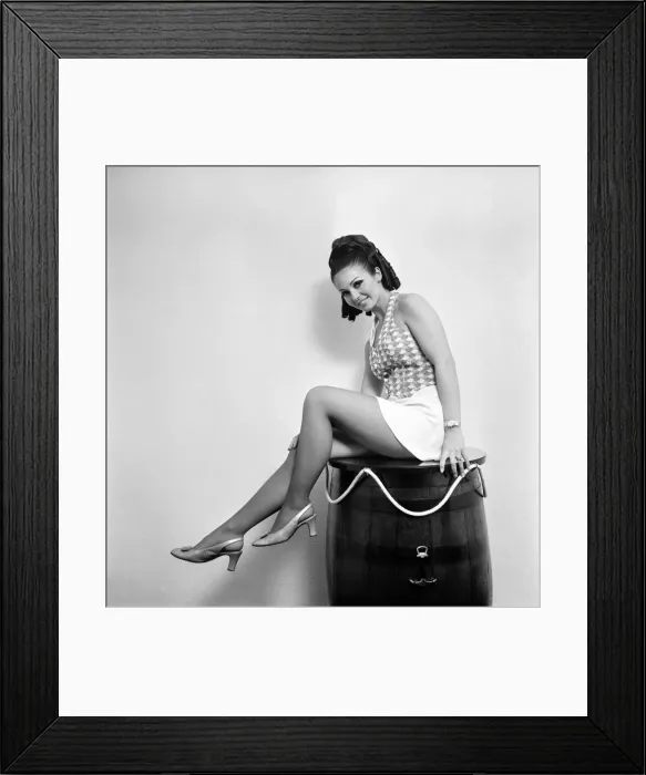 Framed Print : Woman wearing a patterned top and short skirt posing with a barrel Framed Print : Woman wearing a patterned top and short skirt posing with a barrel