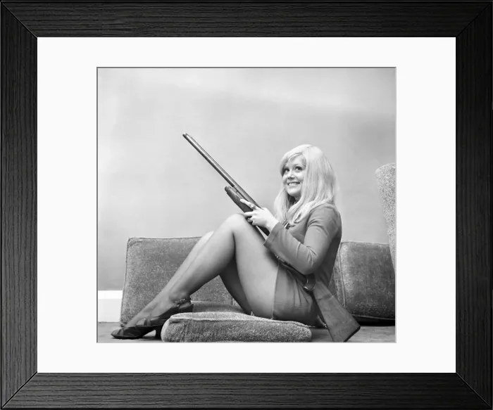 Framed Print : A woman posing wearing a mini dress and holding a shot gun November 1969 Framed Print : A woman posing wearing a mini dress and holding a shot gun November 1969