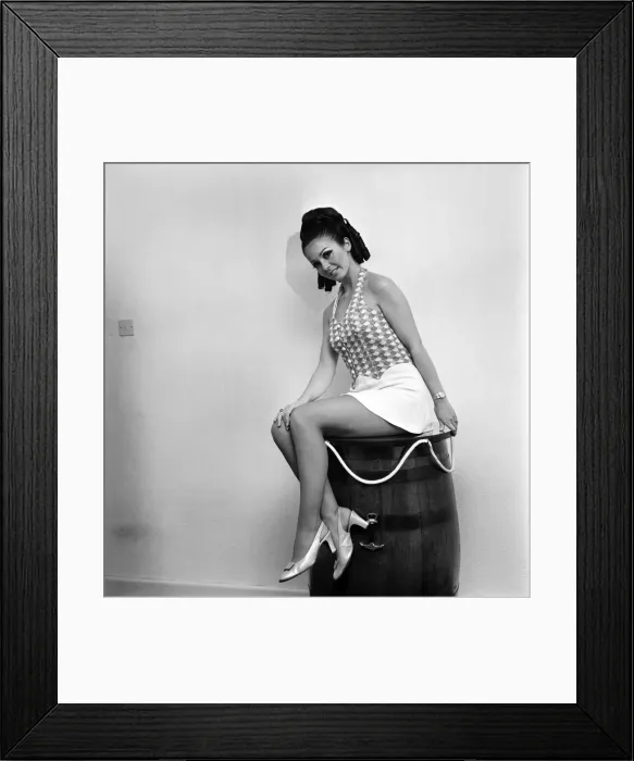 Framed Print : Woman wearing a patterned top and short skirt posing with a barrel