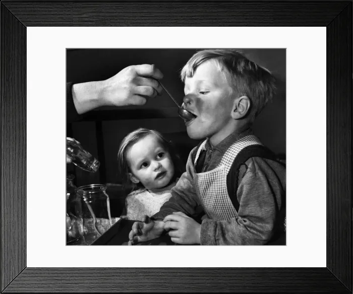 Framed Print : Little girl watches a boy being fed. February 1953 D740 Framed Print : Little girl watches a boy being fed. February 1953 D740
