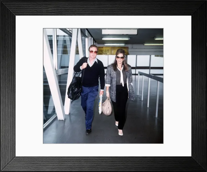 Framed Print : Jackie Collins Writer walking through Heathrow airport with Michael Caine