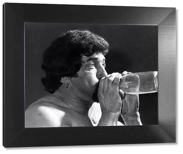 Male Stripper mel blowing into a milk bottle. June 1977 P018599
