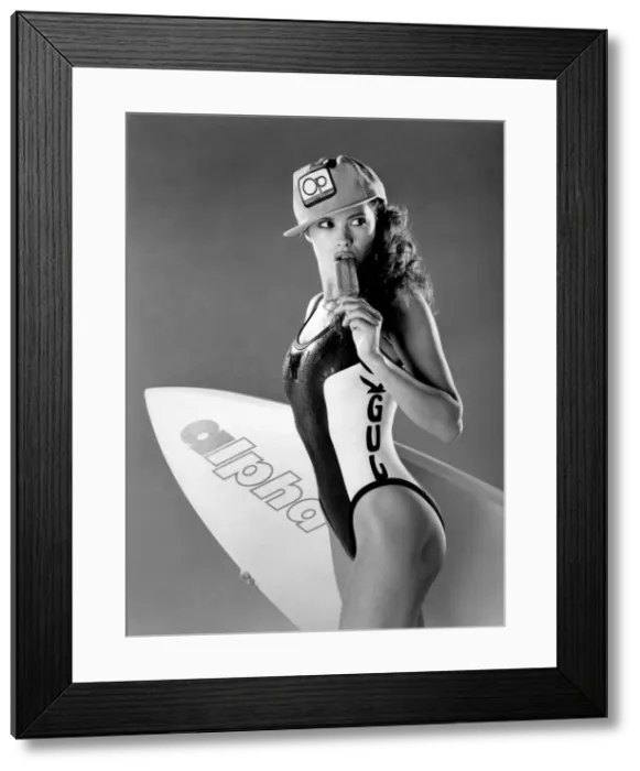 Framed Print : Clothing Beach. Model wears baseball cap, swimming costume and eating ice lolly Framed Print : Clothing Beach. Model wears baseball cap, swimming costume and eating ice lolly