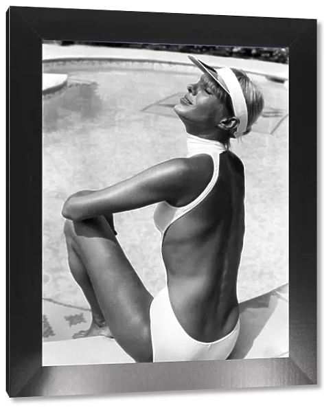 Clothing Beach. Tanned woman models sun visor and white one piece halterneck backless