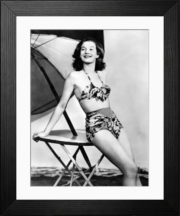 Framed Print : Model wearing a bikini posing by a table underneath an umbrella Framed Print : Model wearing a bikini posing by a table underneath an umbrella