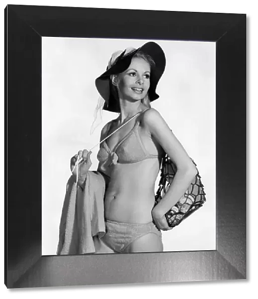 Model wearing a bikini. and hat, carrying a bag over her shoulder August 1970