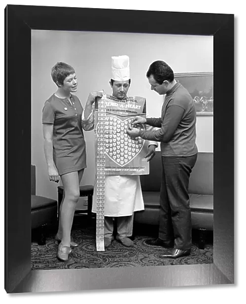 Humour. Man and woman covering a man in a Chefs uniform in plastic hearts