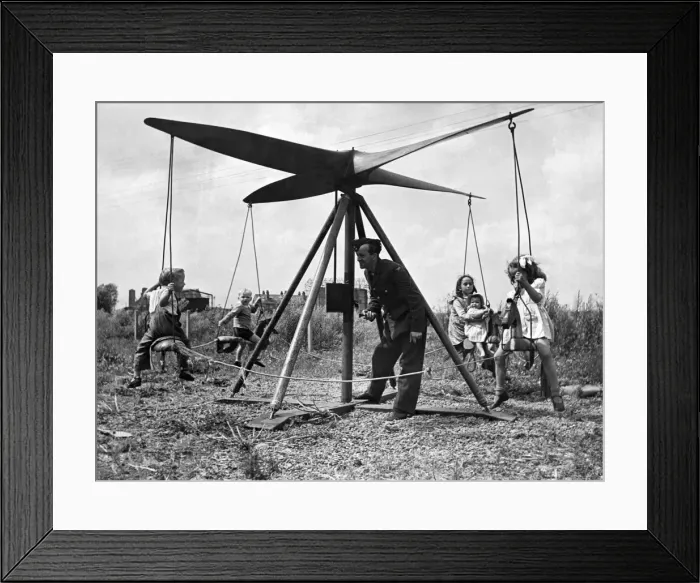 Framed Print : A airman operates a propeller roundabout. Seen here giving local children a ride Framed Print : A airman operates a propeller roundabout. Seen here giving local children a ride