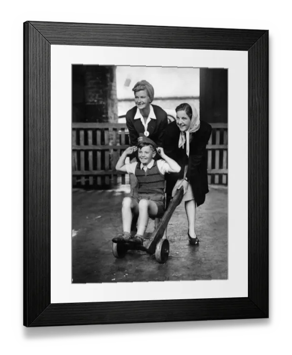 Framed Print : Repatriated civilians. A boy on a sack truck with two girls pushing