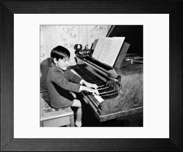Framed Print : Seven year old boy playing songs on the piano which he has written himself Framed Print : Seven year old boy playing songs on the piano which he has written himself