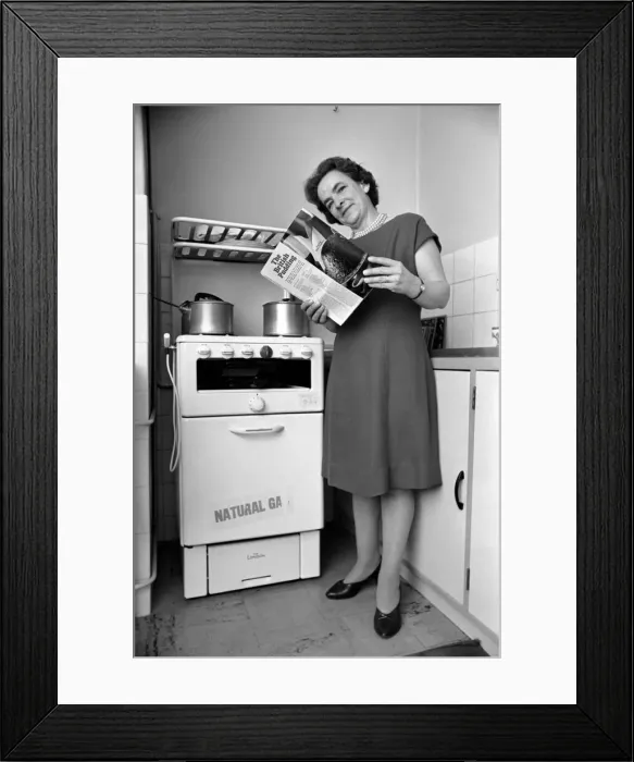 Framed Print : Household - Domestic Chores Cooking. A woman using her gas over in the kitchen of her