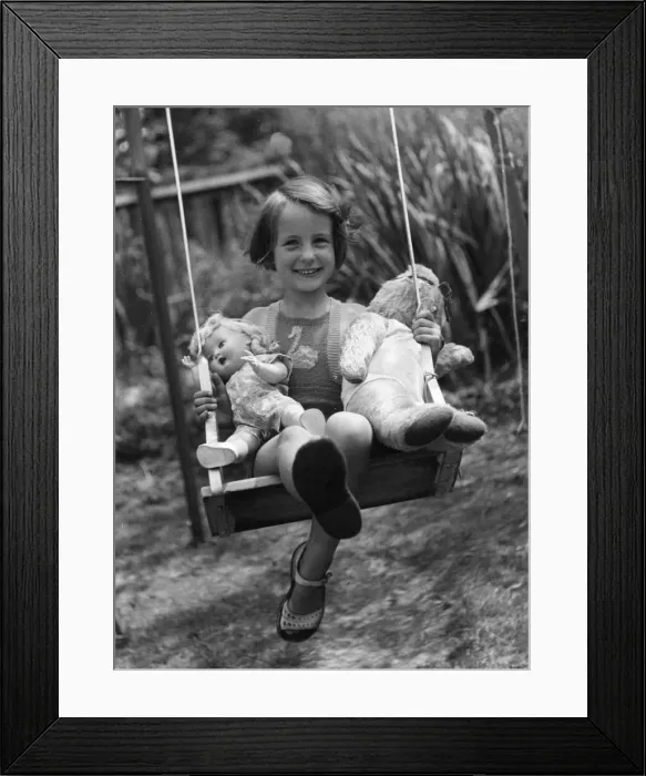 Framed Print : Young girl sitting on her swing in the back garden with her favourite toys Framed Print : Young girl sitting on her swing in the back garden with her favourite toys