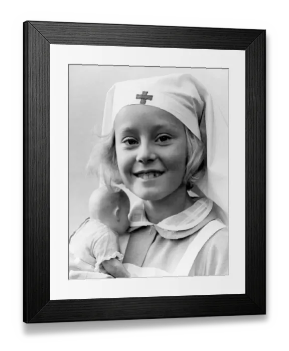 Framed Print : Young girl wearing a nurse costume holding her toy doll Circa 1945 P044505 Framed Print : Young girl wearing a nurse costume holding her toy doll Circa 1945 P044505