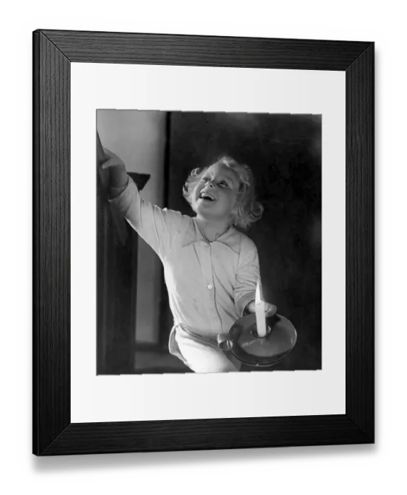 Framed Print : Young girl holding a candle as she climbs the stairs Circa 1945 P044499