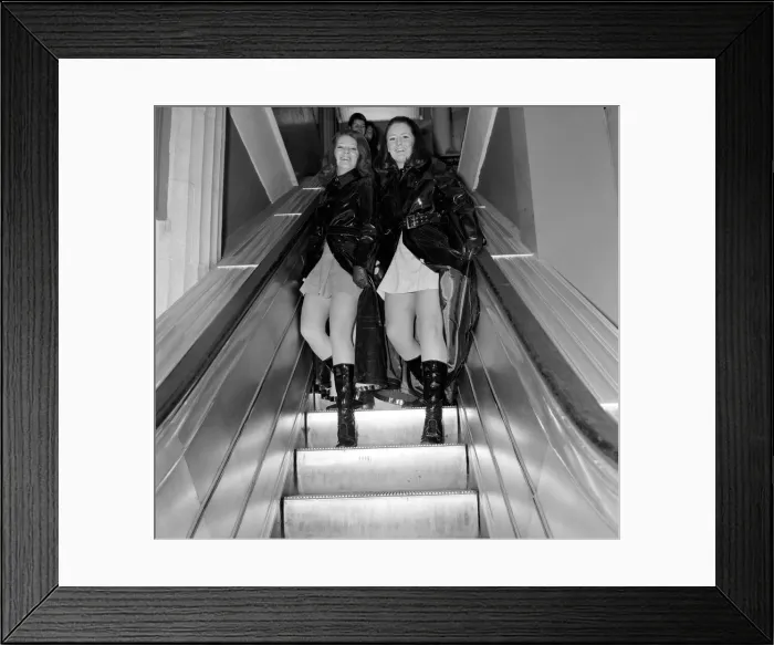Framed Print : Two women lift up their maxi coats on an escalator in a Liverpool store Framed Print : Two women lift up their maxi coats on an escalator in a Liverpool store