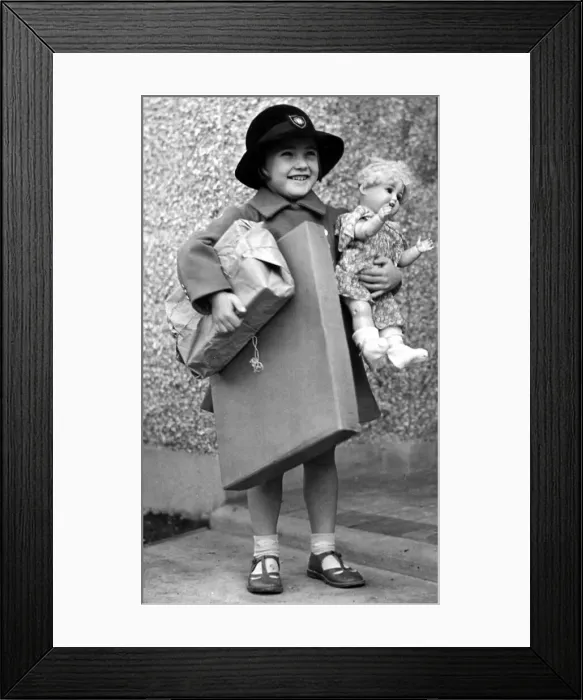 Framed Print : Happy young girl dressed up in coat and hat holding parcels under one arm Framed Print : Happy young girl dressed up in coat and hat holding parcels under one arm