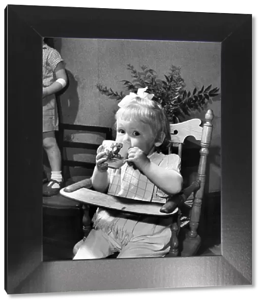 Small girl enjoying a cup of tea. August 1953 D5235