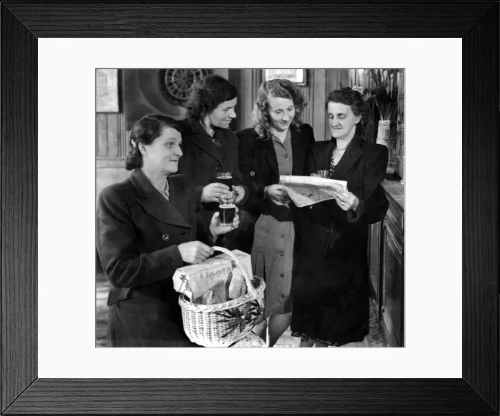 Framed Print : A group of women standing reading the newspaper, one woman in the foreground holding a Framed Print : A group of women standing reading the newspaper, one woman in the foreground holding a