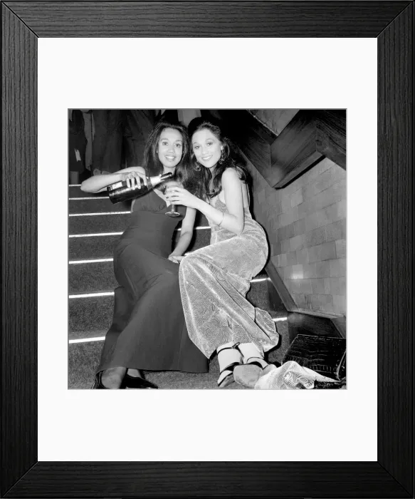 Framed Print : Two girls sitting on the steps pouring a drink during a Christmas party December