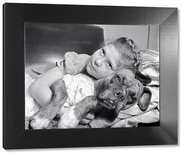 Girl lying down on the sofa with a boxer dog. December 1953 D7354-001