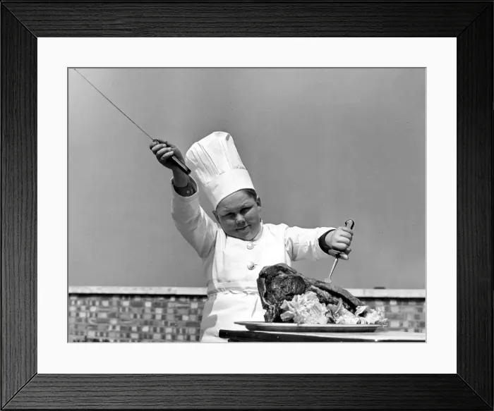 Framed Print : Young boy dressed in a chef uniform including hat, about to carve up a chicken Framed Print : Young boy dressed in a chef uniform including hat, about to carve up a chicken