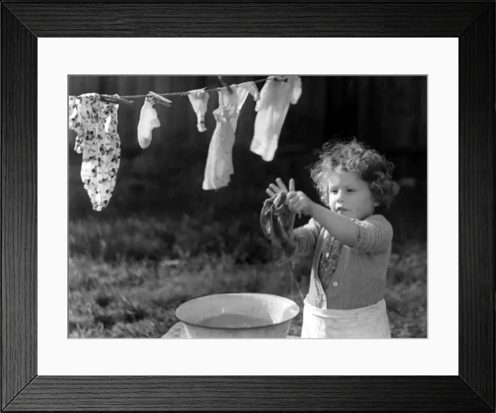 Framed Print : Young girl washing her clothes in a bowl of water and hanging them out to dry Framed Print : Young girl washing her clothes in a bowl of water and hanging them out to dry