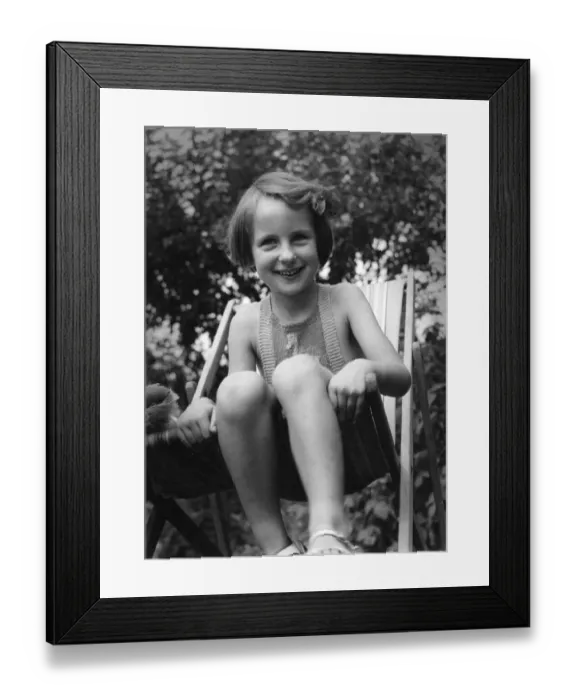 Framed Print : Young girl sitting in a deck chair in the back garden Circa 1945 P044441