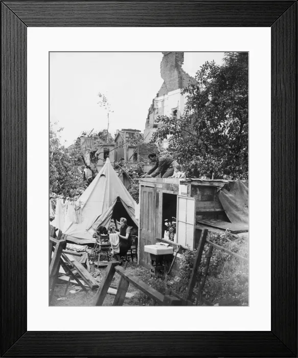 Framed Print : A woman sewing her clothes using a sewing machine as she sits amongst the destruction of Framed Print : A woman sewing her clothes using a sewing machine as she sits amongst the destruction of