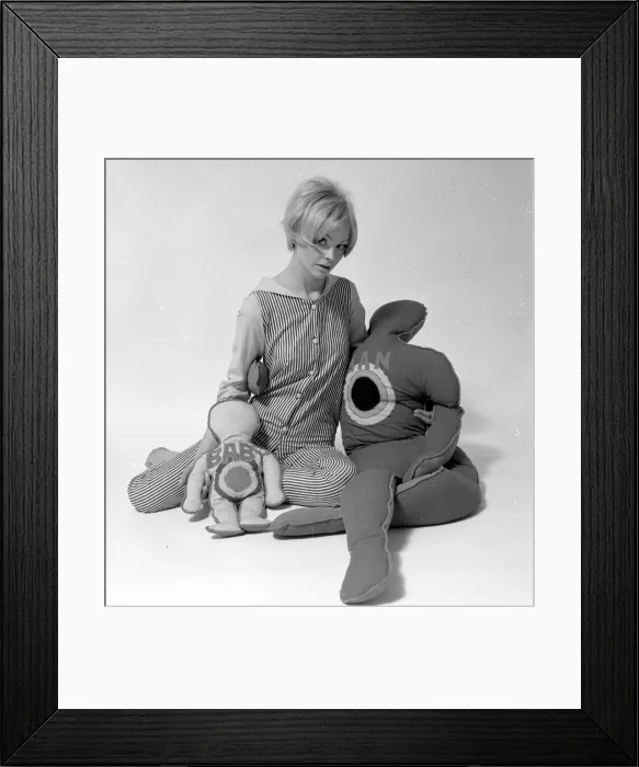Framed Print : Woman Model with pillows in the shape of man and child. January 1968 Framed Print : Woman Model with pillows in the shape of man and child. January 1968