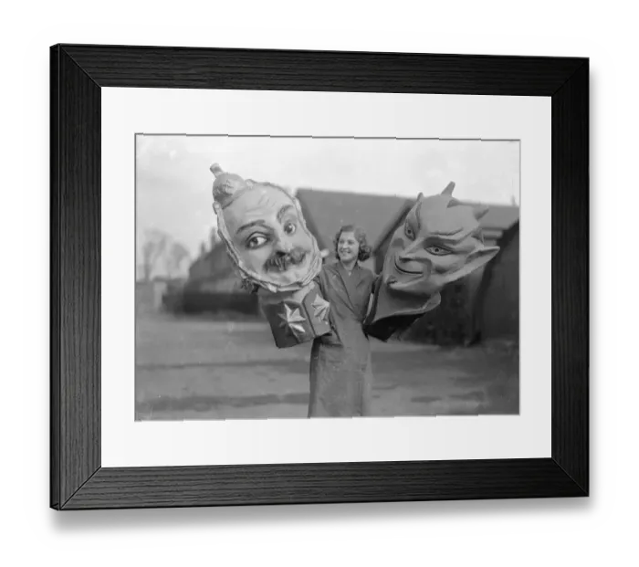 Framed Print : Woman holding two giant masks of the devil at the Twickenham Garden Fete. Circa 1930 Framed Print : Woman holding two giant masks of the devil at the Twickenham Garden Fete. Circa 1930