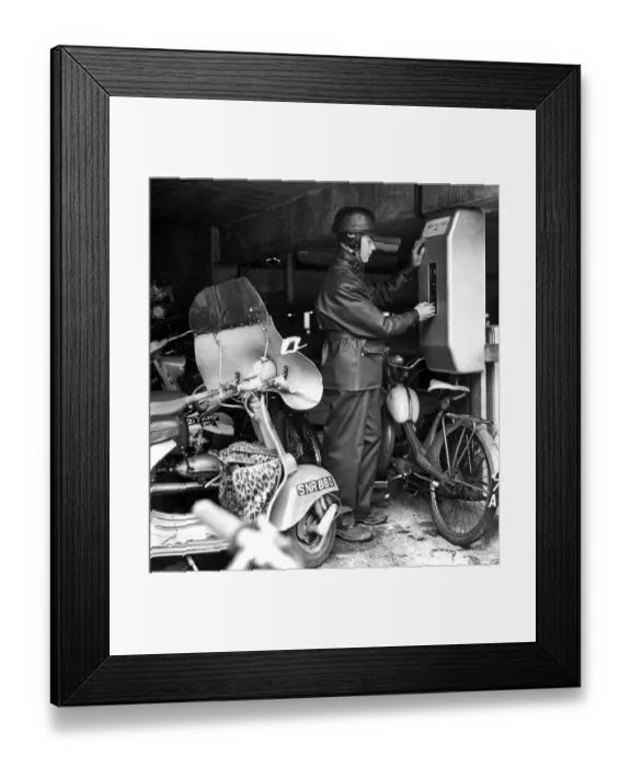 Framed Print : A motor cyclist puts his sixpence in the ticket machine in the new motor cycle Framed Print : A motor cyclist puts his sixpence in the ticket machine in the new motor cycle