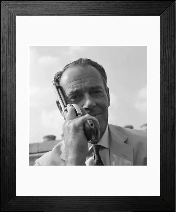 Framed Print : Henry Fonda on the roof of Television House, holding a revolver next to his face