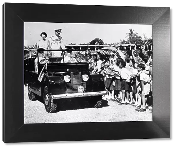 Queen Elizabeth II and Prince Philip smile at waving schoolchildren during heir visit to