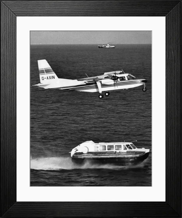 Framed Print : A Britten Norman Islander aircraft flies over a Cushion Craft Hovercraft