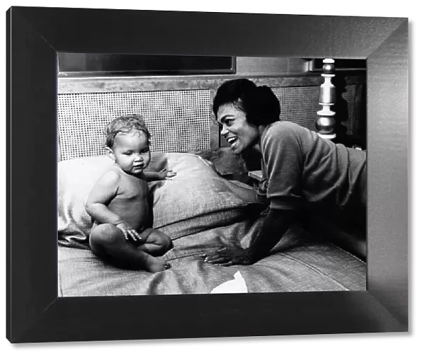 American singer and actress Eartha Kitt, photographed with her baby girl Kitt on her bed