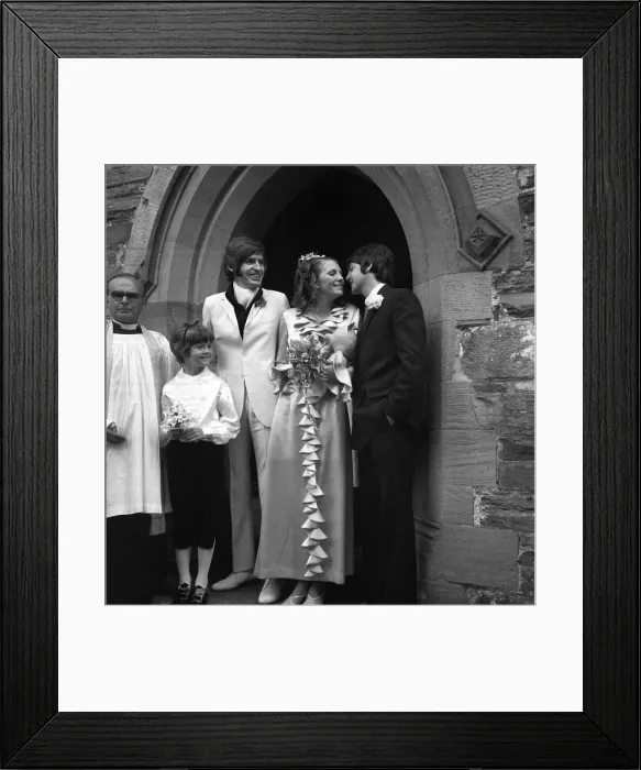 Framed Print : Mike McCartneys Wedding. A kiss for the bride from Paul McCartney watched by Framed Print : Mike McCartneys Wedding. A kiss for the bride from Paul McCartney watched by