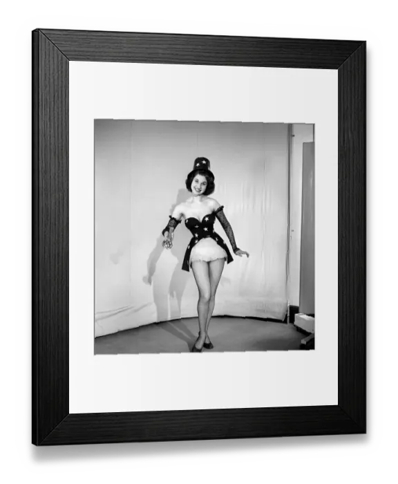 Framed Print : Woman cinema usher wearing star pattern top hat and dress holding a torch. 1959 E41
