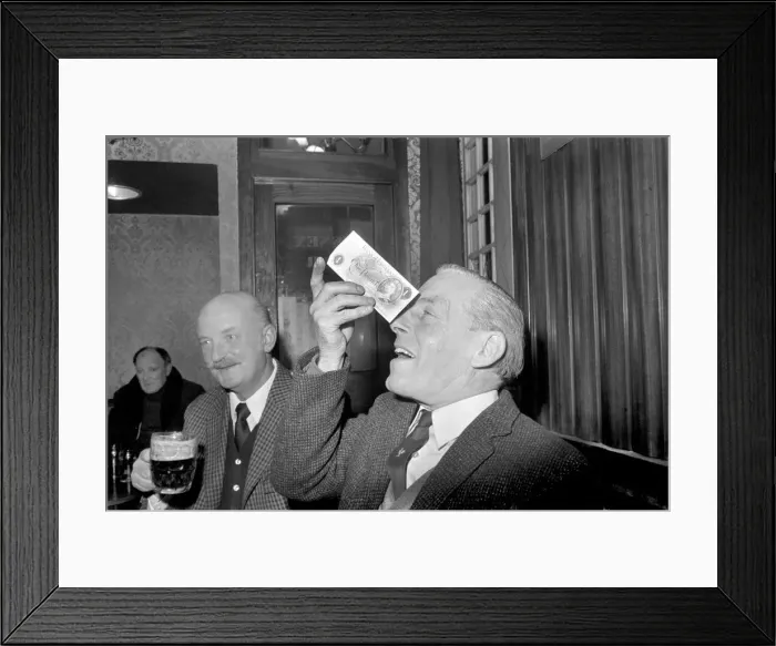 Framed Print : Humour / Unusual. John Mitchell balancing a pound note. February 1975 75-00662-002 Framed Print : Humour / Unusual. John Mitchell balancing a pound note. February 1975 75-00662-002