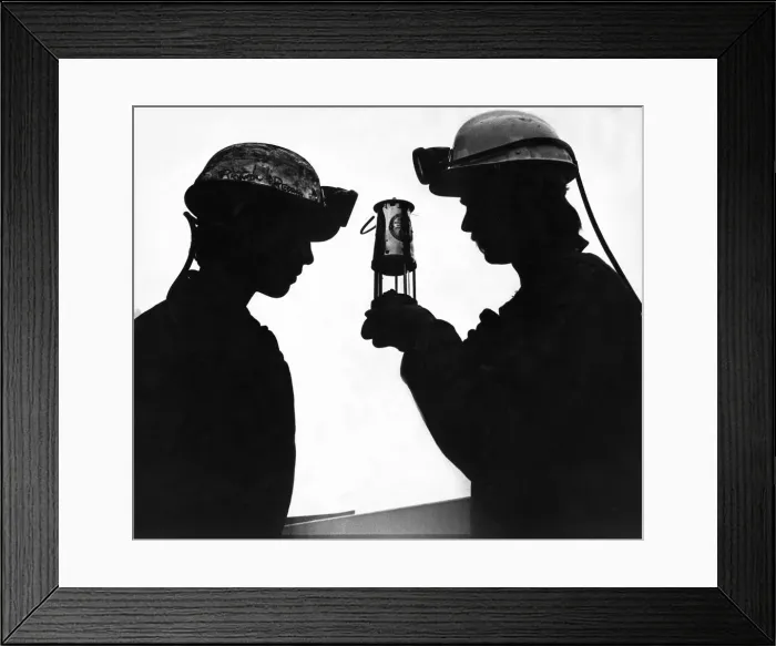 Framed Print : A modern day miner looking at and old miners lamp