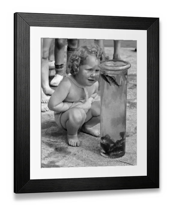 Framed Print : Children seen here with their days catch in a jar on the banks of the River Lea