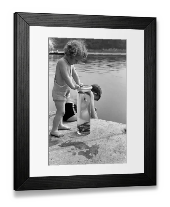 Framed Print : Children seen here with their days catch in a jar on the banks of the River Lea