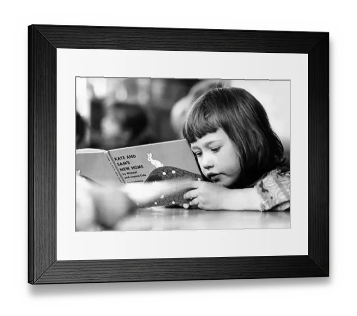 Framed Print : A young girl engrossed in a book at school