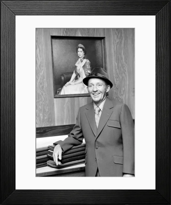 Framed Print : Bing Crosby pictured in the exclusive tailors shop infront of a portrait of HM Framed Print : Bing Crosby pictured in the exclusive tailors shop infront of a portrait of HM
