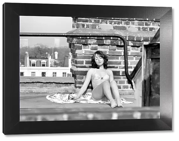 A model wearing a bikini as she subathes on a rooftop on Kings Road in Chelsea, London