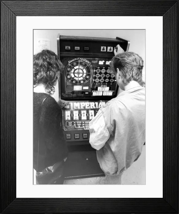 Framed Print : Young people playing on a one armed bandit or electronic gaming machine in September 1983