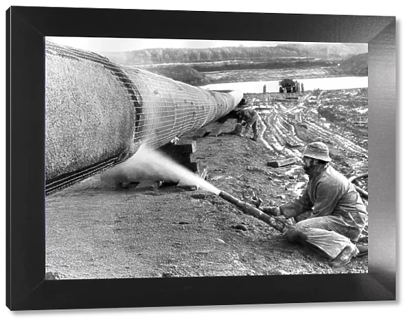 A workman sprays on the gas pipelines concrete coat in December 1974